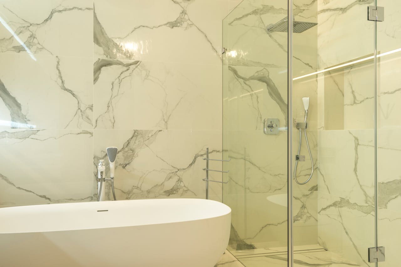 Luxurious marble bathroom featuring a modern bathtub and glass shower enclosure.